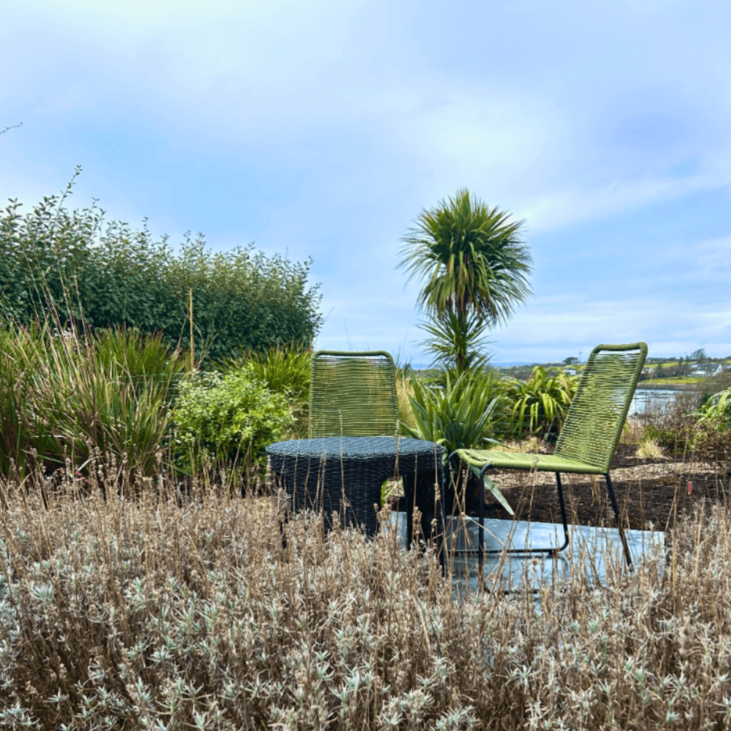 Garden seating area overlooking the sea with coastal landscape design