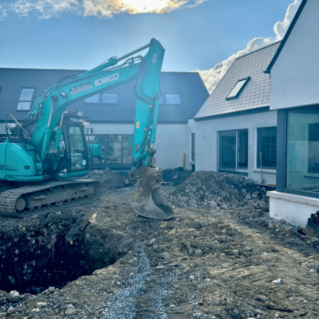 Backhoe excavating soil in a residential Galway garden for landscaping or drainage work.